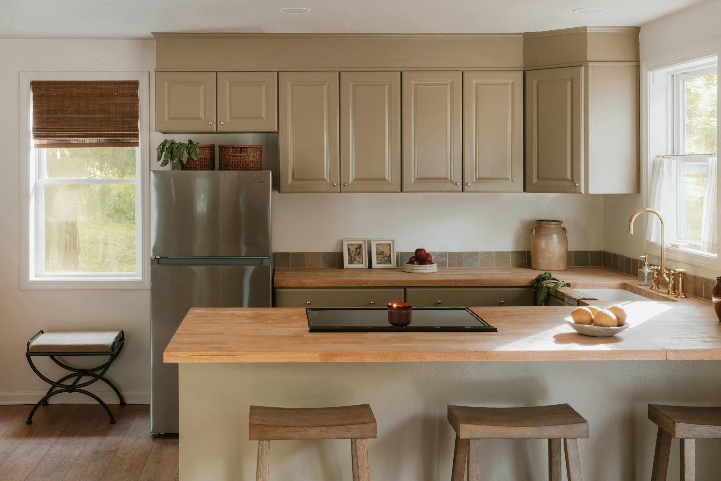 A warm, sunlit kitchen with sage cabinetry — the kind of space we keep spotless